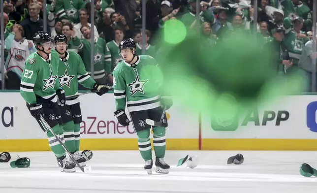 A cowboy hat is thrown onto the ice as Dallas Stars' Mason Marchment (27) and Miro Heiskanen, center, celebrate with Mikael Granlund, right, after Granlund earned a hat trick in the third period of Game 4 of a second-round NHL hockey playoff series in Dallas, Tuesday, May 13, 2025. (AP Photo/Gareth Patterson)