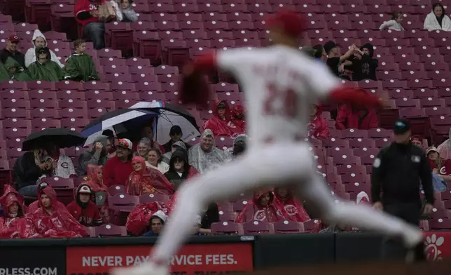 Fans sit in the rain as Cincinnati Reds pitcher Nick Martinez throws during the sixth inning of a baseball game against the Washington Nationals, Sunday, May 4, 2025, in Cincinnati. (AP Photo/Carolyn Kaster)