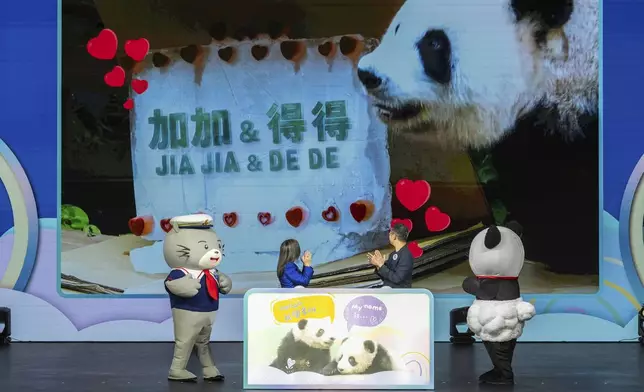 The name of the Hong Kong-born giant panda twin cubs Jia Jia and De De are displayed on the screen as Rosanna Law, secretary for Culture, Sports and Tourism of Hong Kong, left and Paulo Pong, chairman of the Ocean Park attend the naming ceremony in Hong Kong, Tuesday, May 27, 2025. (AP Photo/Chan Long Hei)