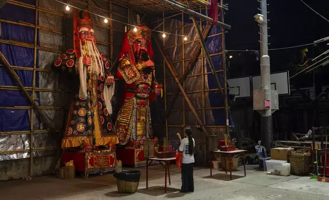 A worshipper prays and burns incense at a temple during the Bun Festival in Cheung Chau Island in Hong Kong, Monday, May 5, 2025. (AP Photo/Chan Long Hei)