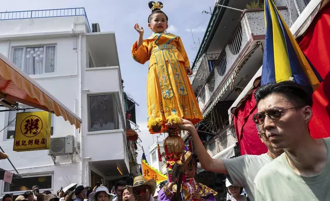 A child is hoisted up as participants take part in the Piu Sik Parade at the Bun Festival in Cheung Chau Island in Hong Kong, Monday, May 5, 2025. (AP Photo/Chan Long Hei)