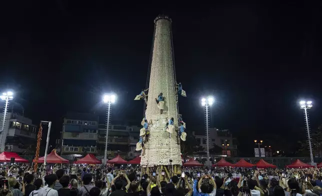 Participants take part in a bun scrambling competition during the Bun Festival in Cheung Chau Island in Hong Kong, Tuesday, May 6, 2025. (AP Photo/Chan Long Hei)