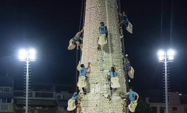 Participants climb up a tower covered with plastic buns during the Bun Festival in Cheung Chau Island in Hong Kong, Tuesday, May 6, 2025. (AP Photo/Chan Long Hei)