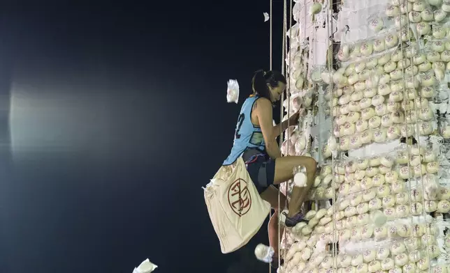 A participant collects buns from a tower covered with plastic buns during the Bun Festival in Cheung Chau Island in Hong Kong, Tuesday, May 6, 2025. (AP Photo/Chan Long Hei)