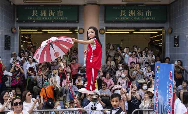 A child is hoisted up as participants take part in the Piu Sik Parade at the Bun Festival in Cheung Chau Island in Hong Kong, Monday, May 5, 2025. (AP Photo/Chan Long Hei)