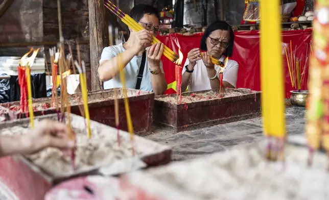 Worshippers burn incense at a temple during the Bun Festival in Cheung Chau Island in Hong Kong, Monday, May 5, 2025. (AP Photo/Chan Long Hei)