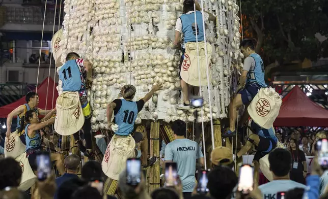 Participants collect buns from a tower covered with plastic buns during the Bun Festival in Cheung Chau Island in Hong Kong, Tuesday, May 6, 2025. (AP Photo/Chan Long Hei)