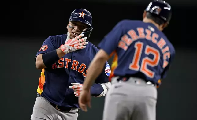 Houston Astros' Isaac Paredes, left, rounds the bases past third base coach Tony Perezchica (12) after hitting a three-run home run off Texas Rangers relief pitcher Robert Garcia during the eighth inning of a baseball game in Arlington, Texas, Sunday, May 18, 2025. (AP Photo/Jerome Miron)