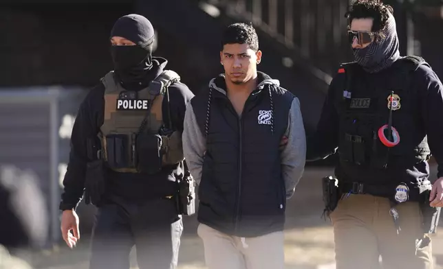 File - Law officials escort a suspect from an apartment to a waiting utility vehicle for transport during a raid Feb. 5, 2025, in east Denver. (AP Photo/David Zalubowski, File)