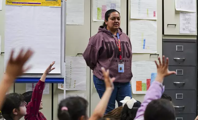 Students raise their hands to be called on by second grade math teacher Johanna Correa at Place Bridge Academy, May 20, 2025, in Denver. (AP Photo/Rebecca Slezak)