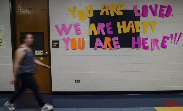 A staff member walks past a message to students that hangs on the wall at Place Bridge Academy, May 20, 2025, in Denver. (AP Photo/Rebecca Slezak)