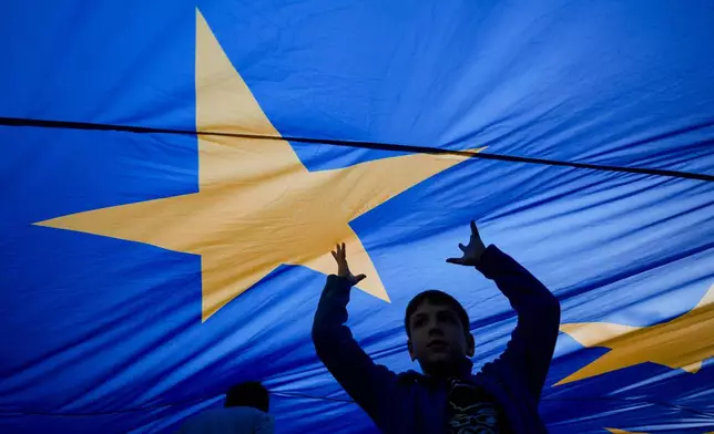 FILE - Children play under an European Union flag during an electoral rally of presidential candidate Nicusor Dan, a week ahead of the second round of the country's presidential election redo in Bucharest, Romania, Sunday, May 11, 2025. (AP Photo/Andreea Alexandru, File)