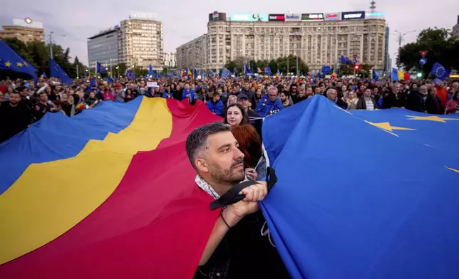 FILE - Demonstrators hold large Romanian and European Union flags during a pro-EU rally ahead of the second round of the presidential election redo in Bucharest, Romania, Friday, May 9, 2025. (AP Photo/Andreea Alexandru, File)