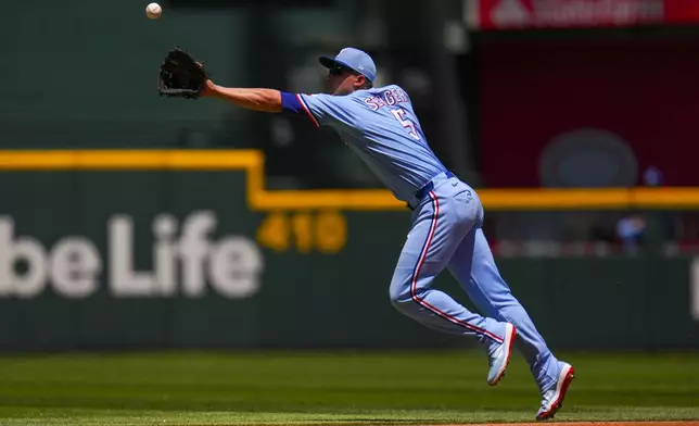 Texas Rangers shortstop Corey Seager reaches for a single by Seattle Mariners' Leo Rivas during the third inning of a baseball game Sunday, May 4, 2025, in Arlington, Texas. (AP Photo/Julio Cortez)