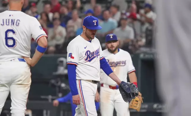 Texas Rangers pitcher Luke Jackson, center, walks to the mound after getting hit by a line drive during the ninth inning of a baseball game against the Colorado Rockies, Monday, May 12, 2025, in Arlington, Texas. (AP Photo/LM Otero)