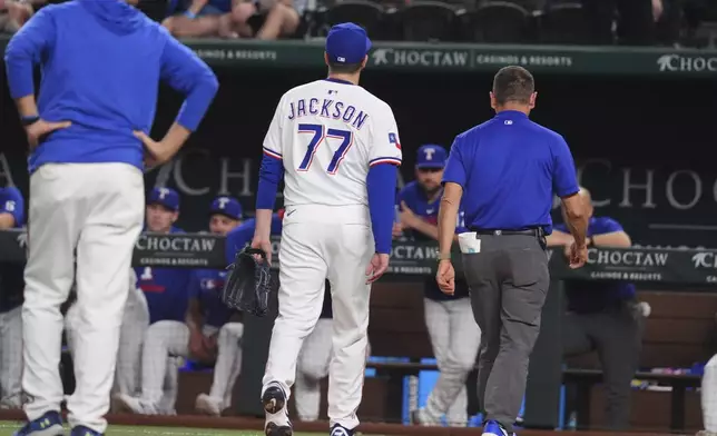Texas Rangers pitcher Luke Jackson (77) leaves after getting hit by a line drive during the ninth inning of a baseball game against the Colorado Rockies, Monday, May 12, 2025, in Arlington, Texas. (AP Photo/LM Otero)