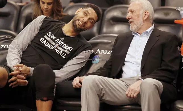 FILE - In this Feb. 28, 2015, file photo, San Antonio Spurs forward Tim Duncan, left, and head coach Gregg Popovich chat on the bench during the first quarter of an NBA basketball game against the Phoenix Suns in Phoenix. (AP Photo/Rick Scuteri, File)