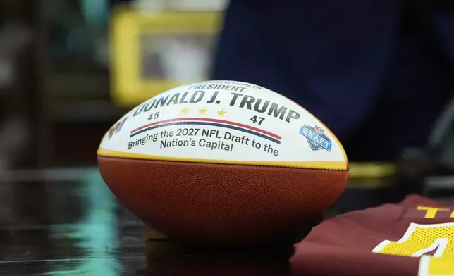 A football presented to President Donald Trump is pictured as Trump speaks during an event to announce that the 2027 NFL Draft will be held on the National Mall, in the Oval Office of the White House, Monday, May 5, 2025, in Washington. (AP Photo/Alex Brandon)