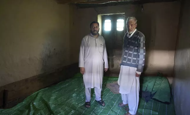 Mohammad Younis Khan, right, and Mohammad Saleem stand in a cowshed where they spent a night, along with 38 others, during artillery shelling from Pakistan, in the border village of Gingal, north of Srinagar, Indian-controlled Kashmir, Wednesday, May 14, 2025. (AP Photo/Dar Yasin)