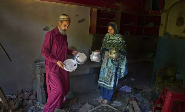 Mohammad Shafi, left, and his wife Shreena Begum show utensils damaged by Pakistani artillery shelling, in the border village of Gingal, north of Srinagar, Indian-controlled Kashmir, Wednesday, May 14, 2025. (AP Photo/Dar Yasin)