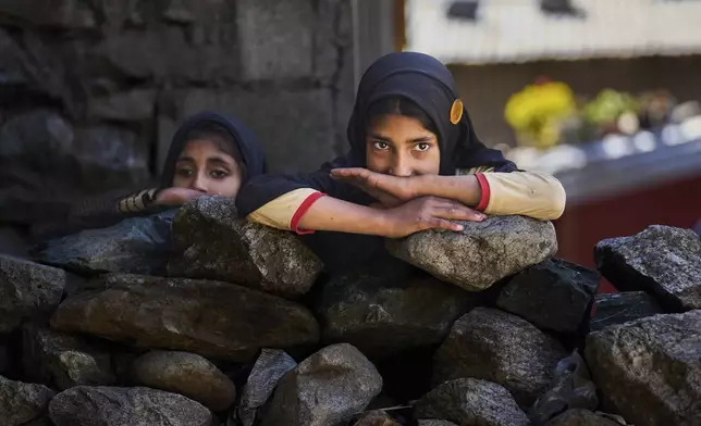 Kashmiri girls look towards houses damaged by artillery shelling from Pakistan upon their return to the border village of Gingal, north of Srinagar, Indian-controlled Kashmir, Wednesday, May 14, 2025. (AP Photo/Dar Yasin)
