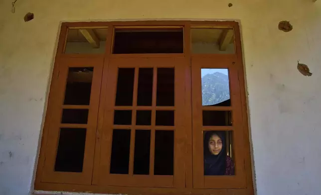 A Kashmiri girl looks out from the damaged window of her house, in the border village of Gingal, north of Srinagar, Indian-controlled Kashmir, Wednesday, May 14, 2025. (AP Photo/Dar Yasin)