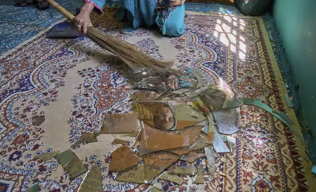A Kashmiri woman sweeps pieces of glass that were shattered from her window during Pakistan artillery shelling in her house in the border village of Gingal, north of Srinagar, Indian-controlled Kashmir, Wednesday, May 14, 2025. (AP Photo/Dar Yasin)