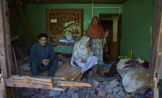 Misra Begum, center, is comforted by her mother in law Sayeeda Begum, as her husband Mahmood Ali sits on a bed inside their bedroom damaged by artillery shelling from Pakistan, in the border village of Gingal, north of Srinagar, Indian-controlled Kashmir, Wednesday, May 14, 2025. (AP Photo/Dar Yasin)