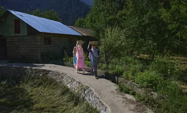 Kashmiri women carry trays filled with cow-dung upon in the border village of Gingal, north of Srinagar, Indian-controlled Kashmir, Wednesday, May 14, 2025. (AP Photo/Dar Yasin)
