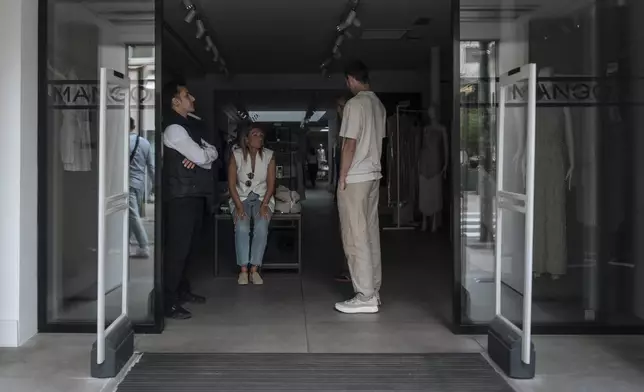 Shop employees wait during an electricity outage in Cannes, southern France, Saturday, May 24, 2025. (AP Photo/Lewis Joly)