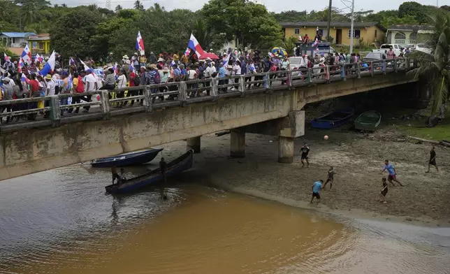 Children play soccer as demonstrators protest a planned reservoir for the Panama Canal at the mouth of the Indio River on Panama's Caribbean coast, Friday, May 16, 2025. (AP Photo/Matias Delacroix)