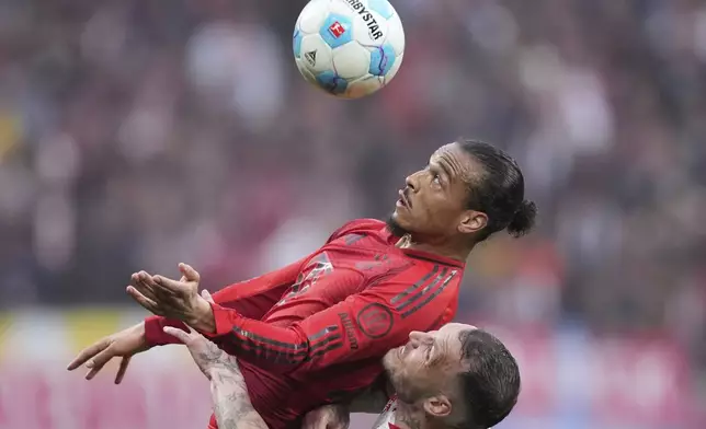 Bayern's Leroy Sane challenges for the ball with Leipzig's David Raum, bottom, during the German Bundesliga soccer match between RB Leipzig and FC Bayern Munich at the Red Bull Arena in Leipzig, Germany, Saturday, May 3, 2025. (AP Photo/Ebrahim Noroozi)