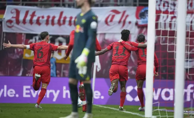 Bayern's Leroy Sane, right, celebrates with teammates after scoring his side's third goal during the German Bundesliga soccer match between RB Leipzig and FC Bayern Munich at the Red Bull Arena in Leipzig, Germany, Saturday, May 3, 2025. (AP Photo/Ebrahim Noroozi)