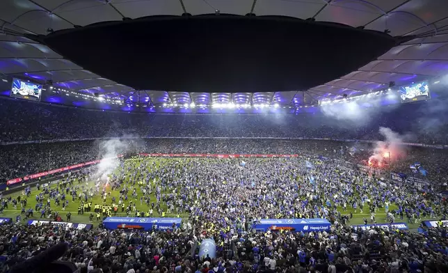 Hamburg fans storm the pitch after the match and celebrate promotion following a Bundesliga 2 soccer game between Hamburger SV and SSV Ulm 1846 in Hamburg, Germany, Saturday, May 10, 2025. (Marcus Brandt/dpa via AP)