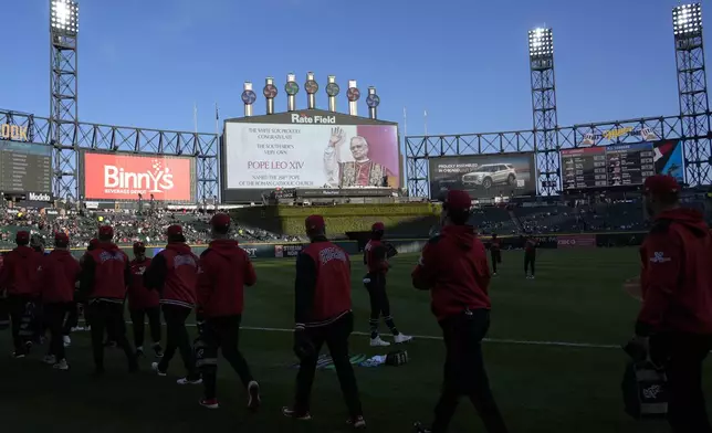 Chicago White Sox players walk on the field as the scoreboard honors Pope Leo XIV before a baseball game against the Miami Marlins, Friday, May 8, 2025, in Chicago. (AP Photo/David Banks)