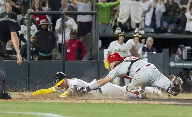 Philadelphia Phillies catcher J.T. Realmuto, right, tags out Athletics' Logan Davidson on a challenge during the 10th inning of a baseball game Saturday, May 24, 2025, in West Sacramento, Calif. (AP Photo/Sara Nevis)