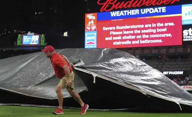 A member of the Busch Stadium grounds crew helps cover the field during a rain delay in a baseball game between the St. Louis Cardinals and the Detroit Tigers Monday, May 19, 2025, in St. Louis. (AP Photo/Jeff Roberson)