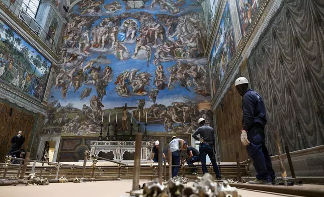 In this image taken on Monday, April 28, 2025, and made available Saturday, May 3, 2025, by Vatican Media, workers prepare the Sistine Chapel at the Vatican, where the upcoming conclave will start May 7, backdropped by Michelangelo Buonarroti's fresco 'The Last Judgement'. (Vatican Media via AP)