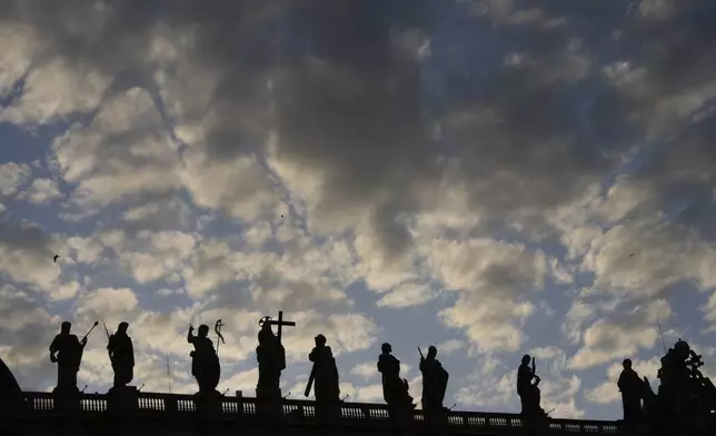 Statues of the Bernini Colonnade are silhouetted against a cloudy sky during the cardinals' conclave to elect a new pope, at the Vatican, Wednesday, May 7, 2025. (AP Photo/Luca Bruno)