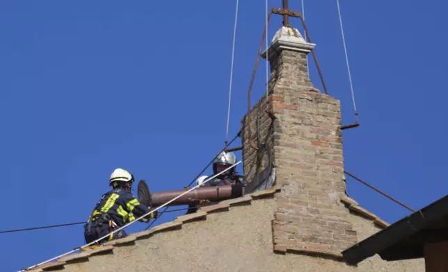 Firefighters place the chimney on the roof of the Sistine Chapel, where cardinals will gather to elect the new pope, at the Vatican, Friday, May 2, 2025. (AP Photo/Gregorio Borgia)