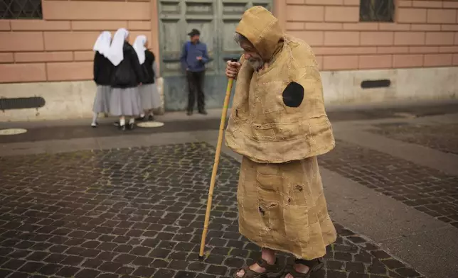 A faithful arrives in St. Peter's Square for the conclave to elect a new pope, at the Vatican, Wednesday, May 7, 2025. (AP Photo/Francisco Seco)