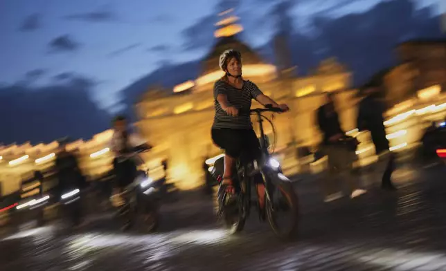 Tourists ride their bicycles next to St. Peter's Basilica, background, at the Vatican, on Monday, May 5, 2025, two days ahead of the upcoming conclave starting on May 7, to elect the 267th Roman pontiff. (AP Photo/Francisco Seco)