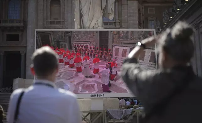 Faithful watch a giant screen showing images of cardinals entering the conclave, in St. Peter's Square at the Vatican, Wednesday, May 7, 2025. (AP Photo/Andrew Medichini)