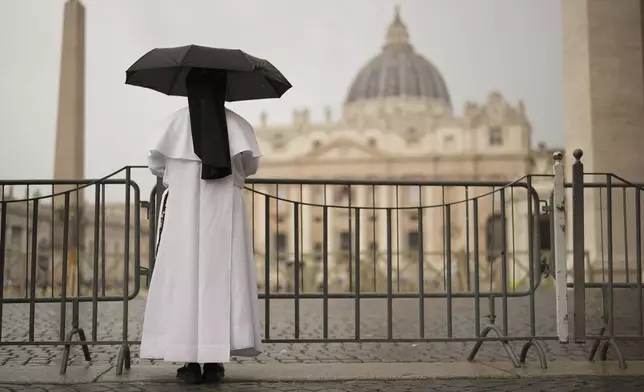 A nun shelters from the rain as she follows a final Mass celebrated by cardinals inside St. Peter's Basilica before the conclave to elect a new pope, in St. Peter's Square, at the Vatican, Wednesday, May 7, 2025. (AP Photo/Francisco Seco)