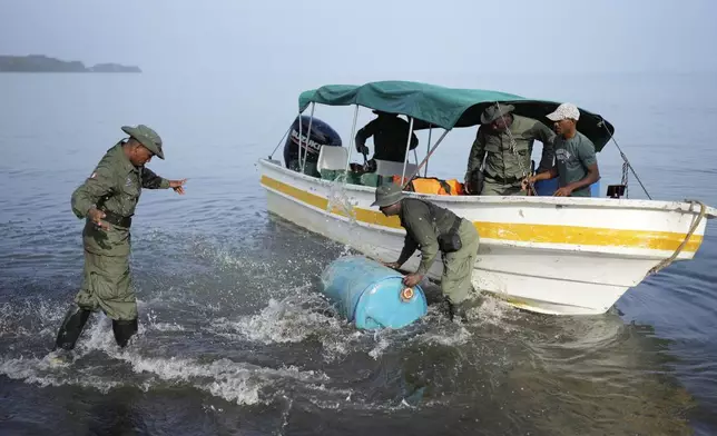 Park rangers unload a container in Punta Patino, Panama, Saturday, April 5, 2025. (AP Photo/Matias Delacroix)