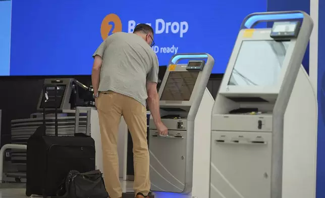 A traveller collects a boarding pass at one of the check-in kiosks at the Southwest Airlines counter in the main terminal of Denver International Airport Friday, May 23, 2025, in Denver. (AP Photo/David Zalubowski)