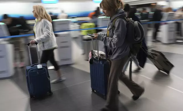 Travelers walk with their luggage through at O'Hare International Airport in Chicago, Friday, May 23, 2025. (AP Photo/Nam Y. Huh)