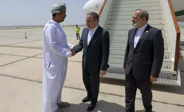 In this photo released by the Iranian Foreign Ministry, Iranian Foreign Minister Abbas Araghchi, center, is welcomed by an unidentified Omani official upon his arrival at Muscat, Oman, for negotiations with U.S. Mideast envoy Steve Witkoff, as Iranian Ambassador to Oman Mousa Farhang stands at right, Sunday, May 11, 2025. (Iranian Foreign Ministry via AP)