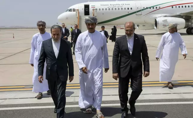 In this photo released by the Iranian Foreign Ministry, Iranian Foreign Minister Abbas Araghchi, left, is welcomed by an unidentified Omani official, center, upon his arrival at Muscat, Oman, for negotiations with U.S. Mideast envoy Steve Witkoff, as Iranian Ambassador to Oman Mousa Farhang walks at right, Sunday, May 11, 2025. (Iranian Foreign Ministry via AP)