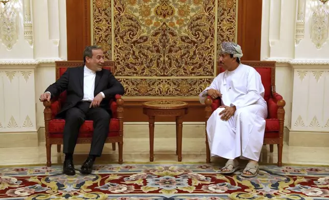 In this photo released by the Iranian Foreign Ministry, Iranian Foreign Minister Abbas Araghchi, left, speaks with an unidentified Omani official upon his arrival in Muscat, Oman, for negotiations with U.S. Mideast envoy Steve Witkoff, Sunday, May 11, 2025. (Iranian Foreign Ministry via AP)